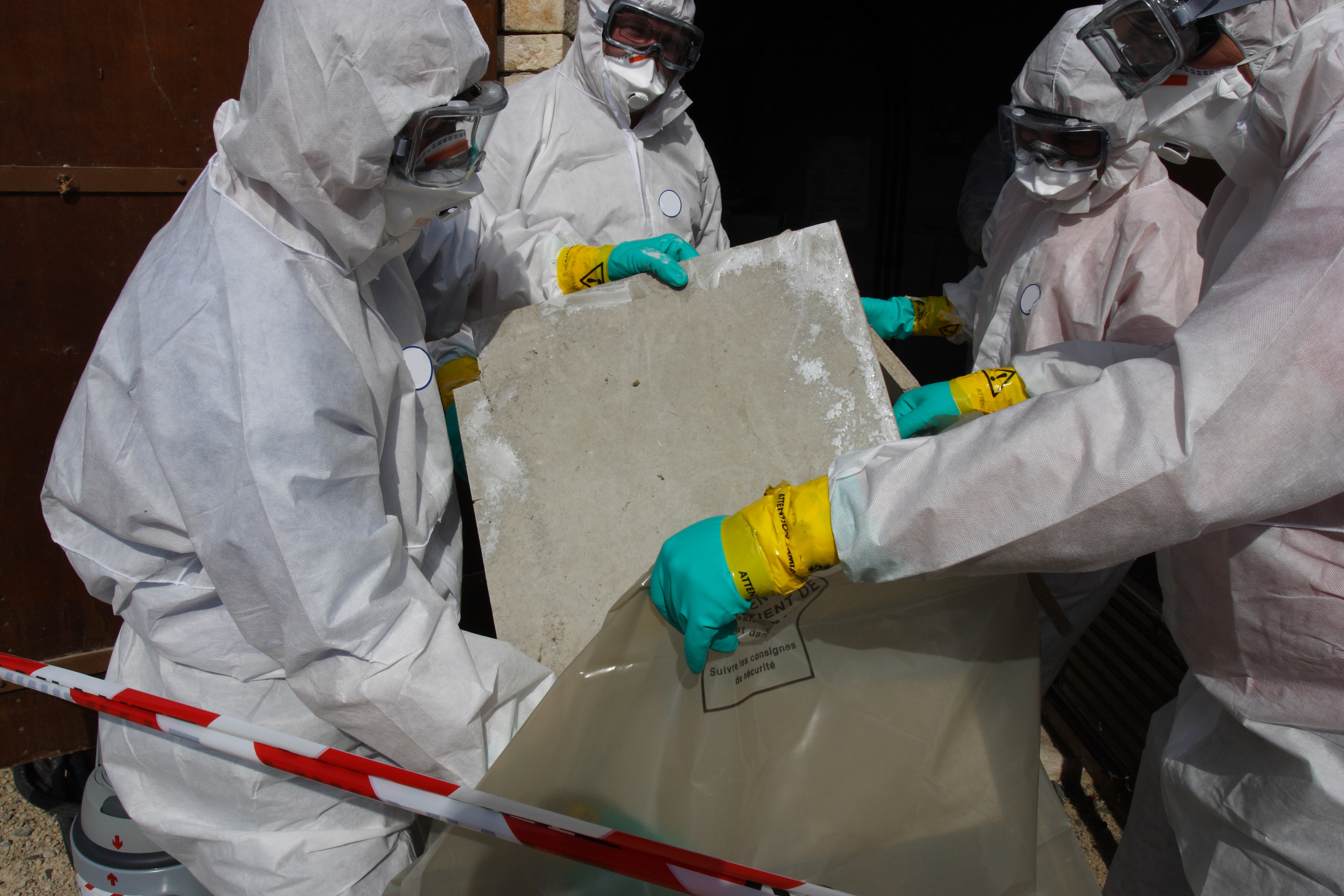 A group of workers in PPE looks for asbestos in homes by performing an asbestos inspection for homeowners.