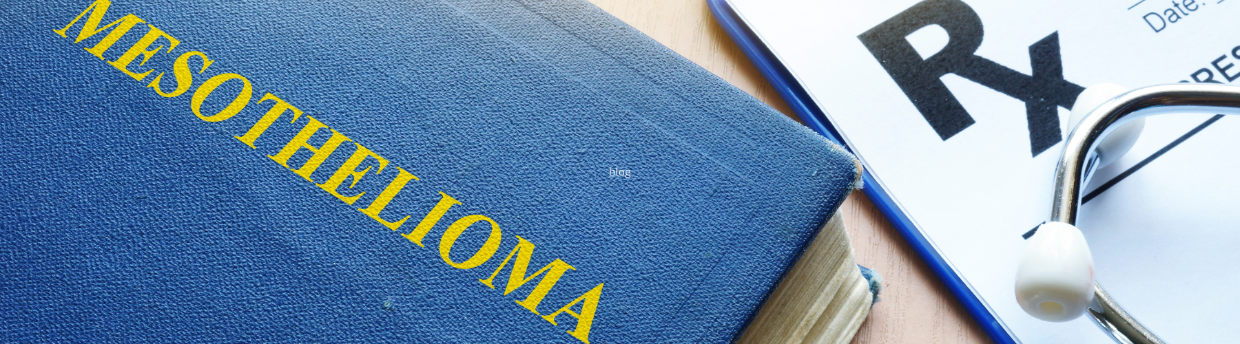 A blue book titled "MESOTHELIOMA" placed on a wooden surface next to a prescription pad marked with "Rx" and a stethoscope, representing medical diagnosis and treatment resources.