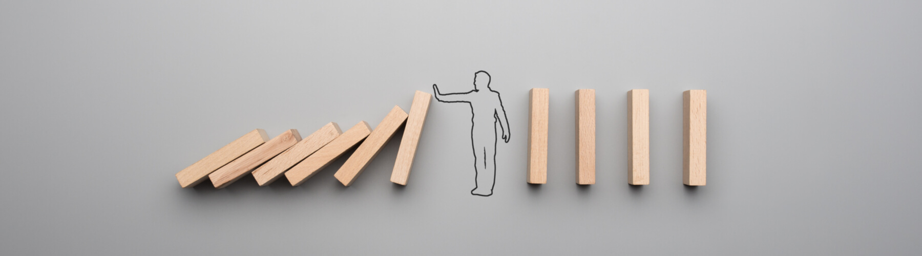 Wide cropped image of the outline of a businessman stopping the domino effect on gray background.