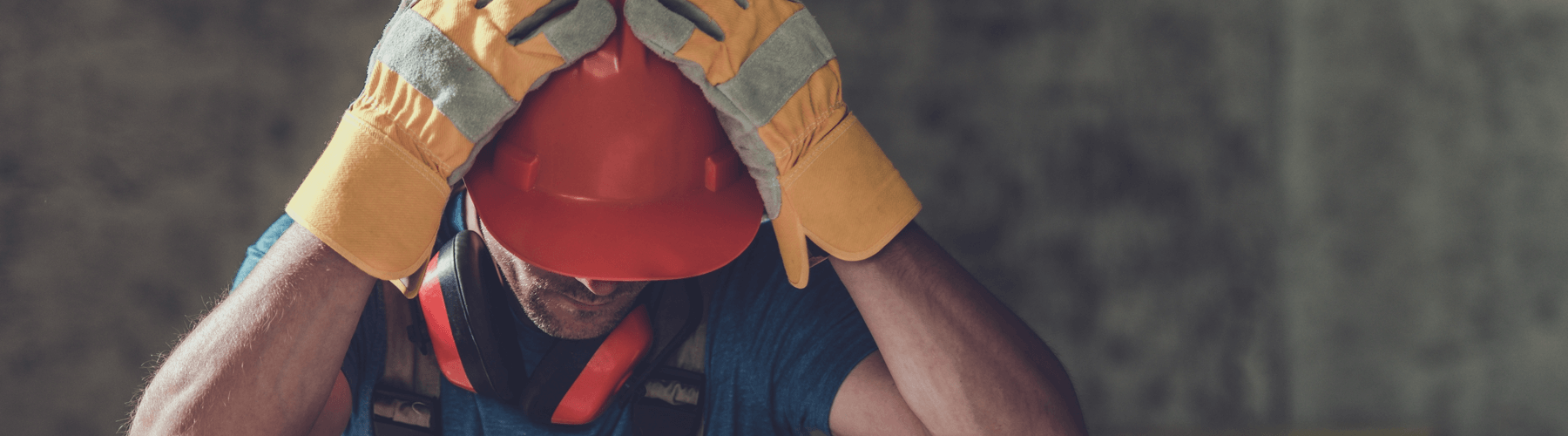 Construction worker with his head in hands head injury, headache, possible traumatic brain injury from incident on a construction site, construction worker in a hard hat