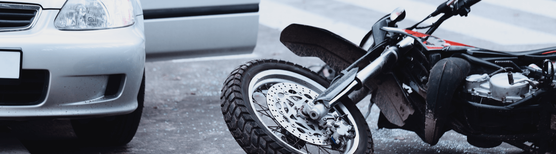 Motorcycle lying on the road and car standing with open door after a collision