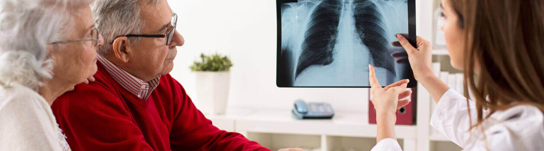 doctor showing lung xray to elderly couple with possible asbestos exposure