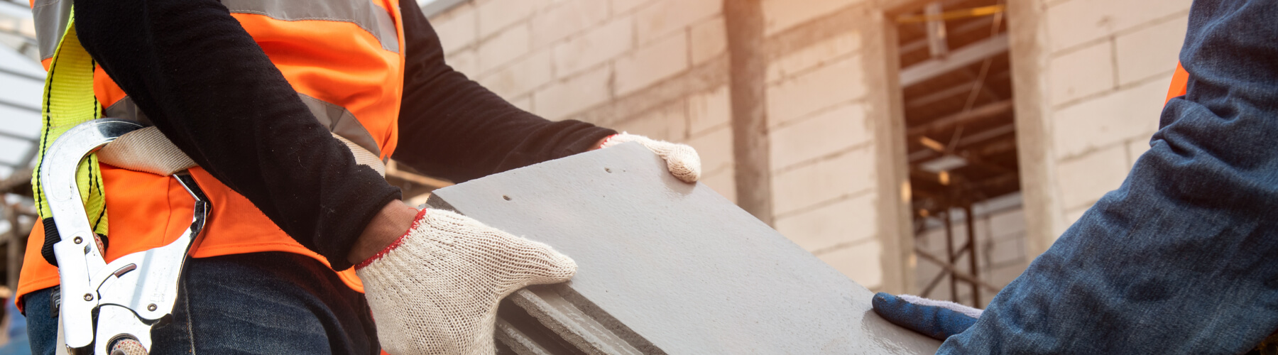 closeup of two construction workers handing blocks of cement or roofing to each other, asbestos exposure concept for construction workers