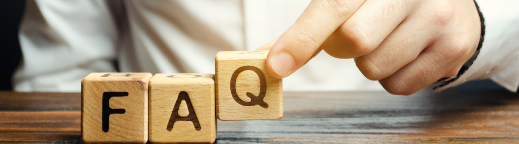 Person puts wooden blocks with the word FAQ