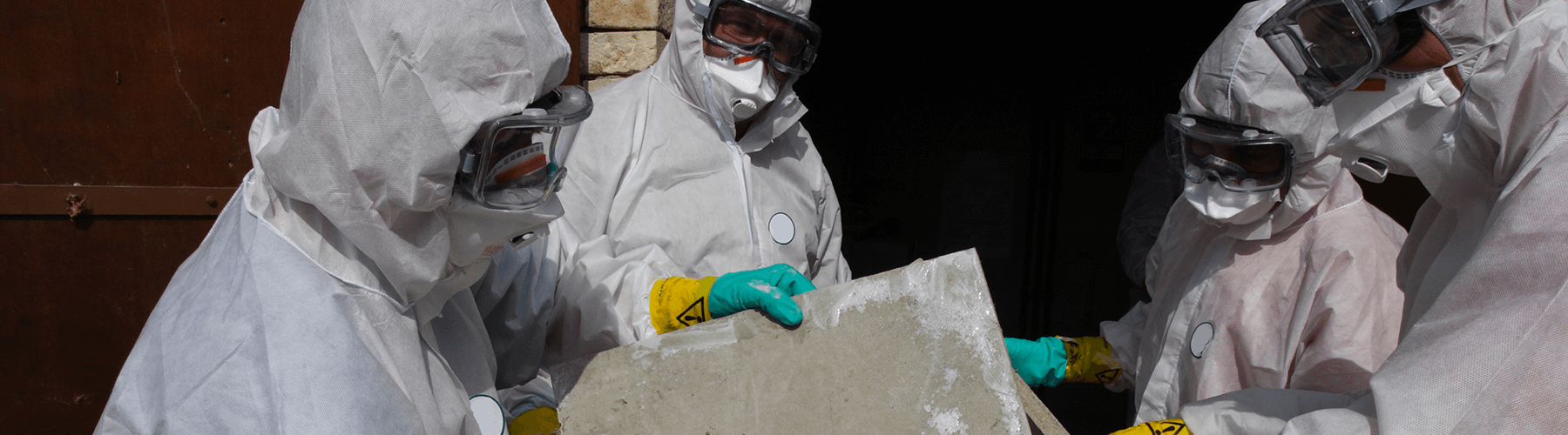 A group of workers in PPE looks for asbestos in homes by performing an asbestos inspection for homeowners.