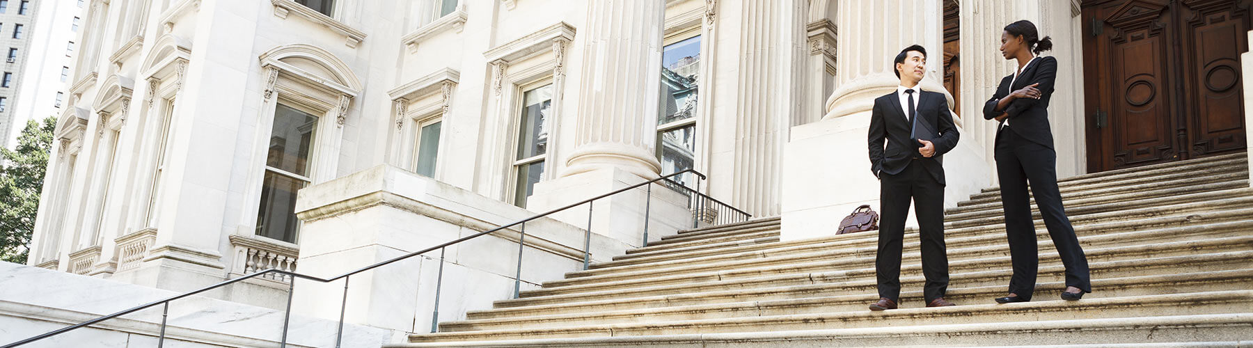 Male and female attorney on steps outside of a courthouse