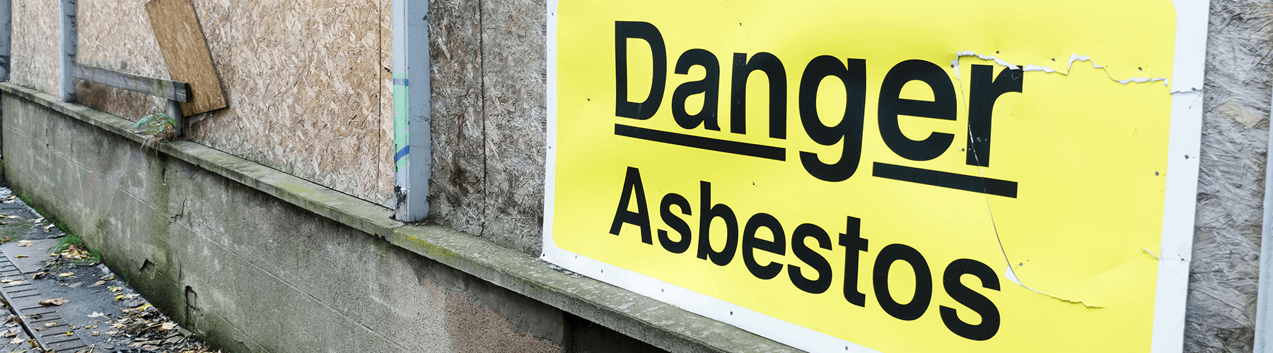 A danger asbestos sign on a building which could lead to secondary asbestos exposure.