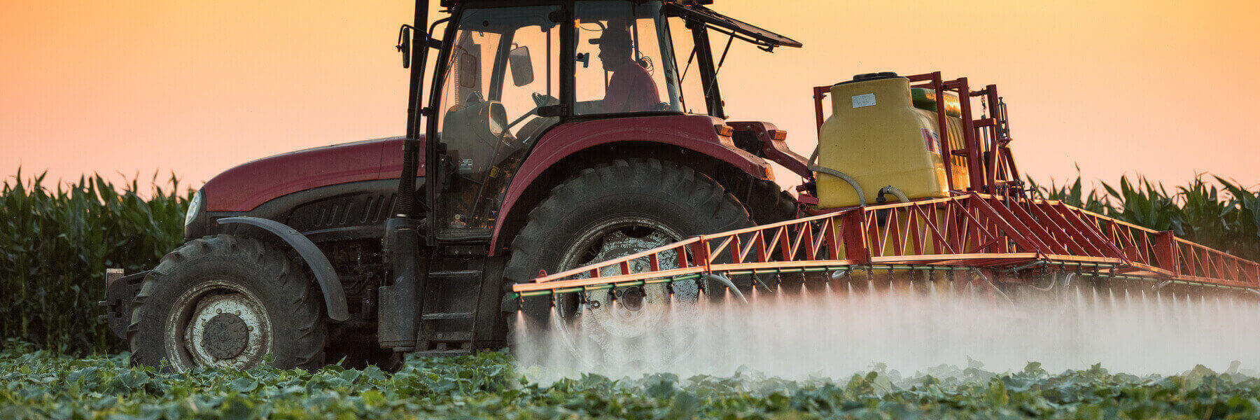 farm equipment spraying pesticide across crops