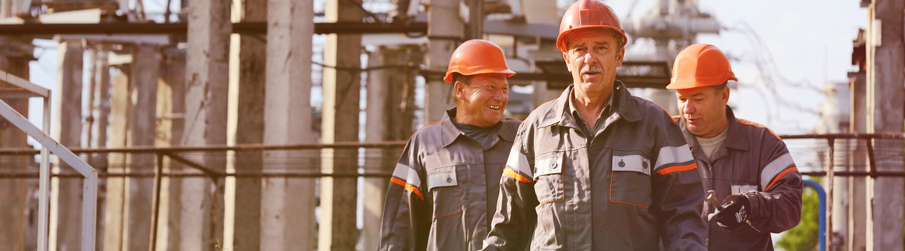 Three male workers walking away from a power plant, end of shit concept. Asbestos exposure concept for power plant workers or industrial facilities
