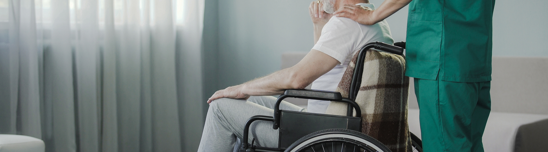 man after serious injury in a wheelchair looking out a window