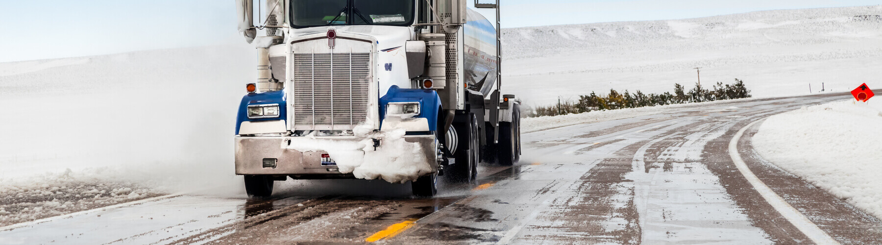 A big truck driving in winter weather conditions