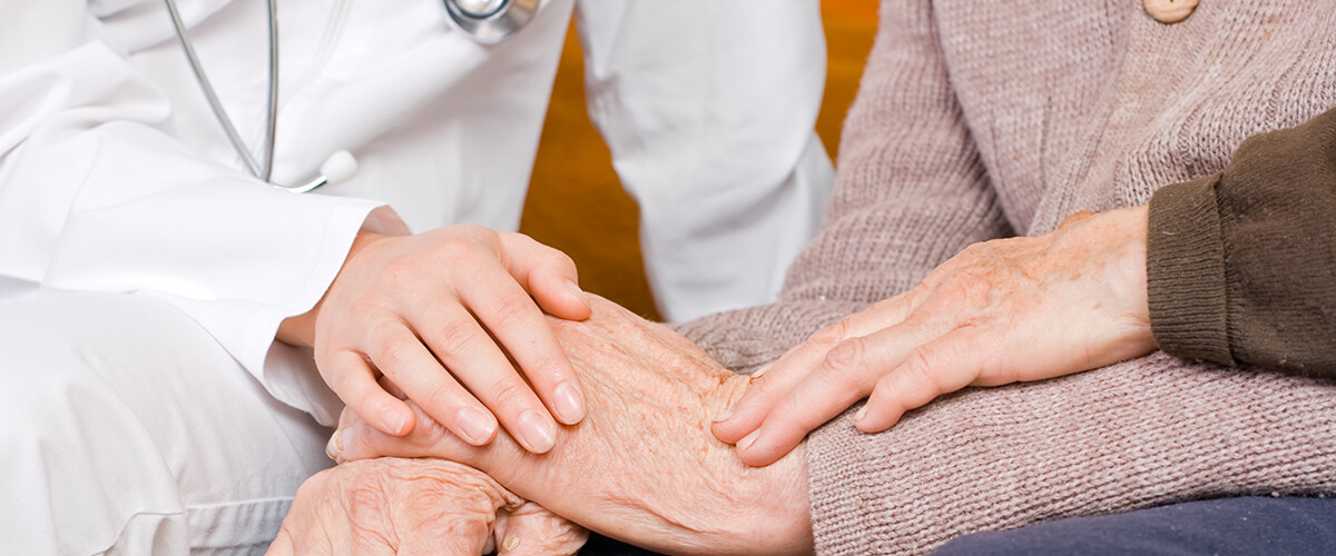 Doctor and daughter holding elderly woman's hand