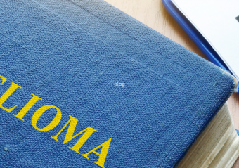 A blue book titled "MESOTHELIOMA" placed on a wooden surface next to a prescription pad marked with "Rx" and a stethoscope, representing medical diagnosis and treatment resources.