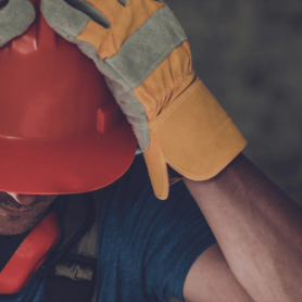 Construction worker with his head in hands head injury, headache, possible traumatic brain injury from incident on a construction site, construction worker in a hard hat
