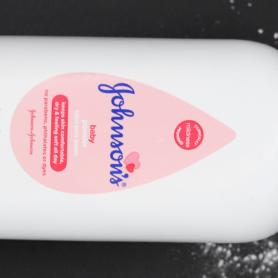 White bottle of Johnson's baby powder isolated on black background