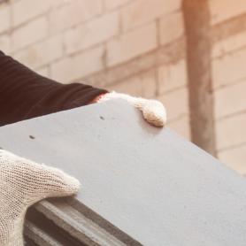closeup of two construction workers handing blocks of cement or roofing to each other, asbestos exposure concept for construction workers