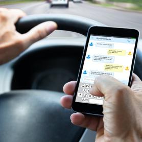 hands holding a phone with text message while driving