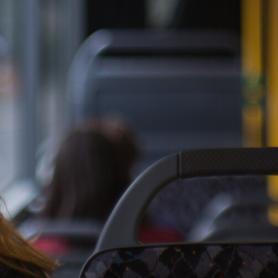 female sitting on a bus listening to headphones