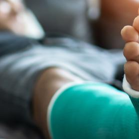 man laying on a couch with a broken foot or ankle, cast on lower leg with crutch propped against couch, commercial injury or premises liability concept