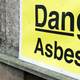 A danger asbestos sign on a building which could lead to secondary asbestos exposure.