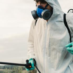 worker in PPE spraying herbicide
