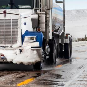 A big truck driving in winter weather conditions