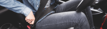 close up image of young adult female wearing jeans buckling her seatbelt in car