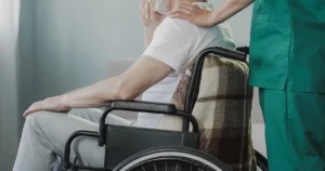 Patient in wheelchair being comforted by nurse