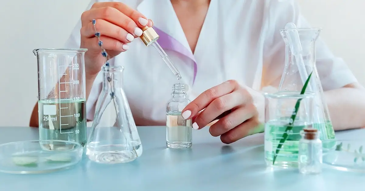 Scientist using a dropper in a laboratory with glass beakers, representing chemical exposure