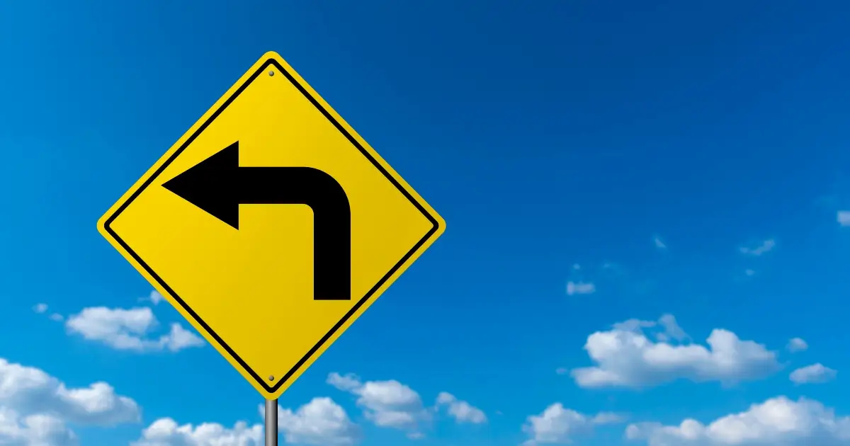 left-turn sign against a bright blue sky