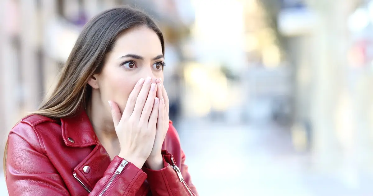 young woman holding her face in surprise & upset
