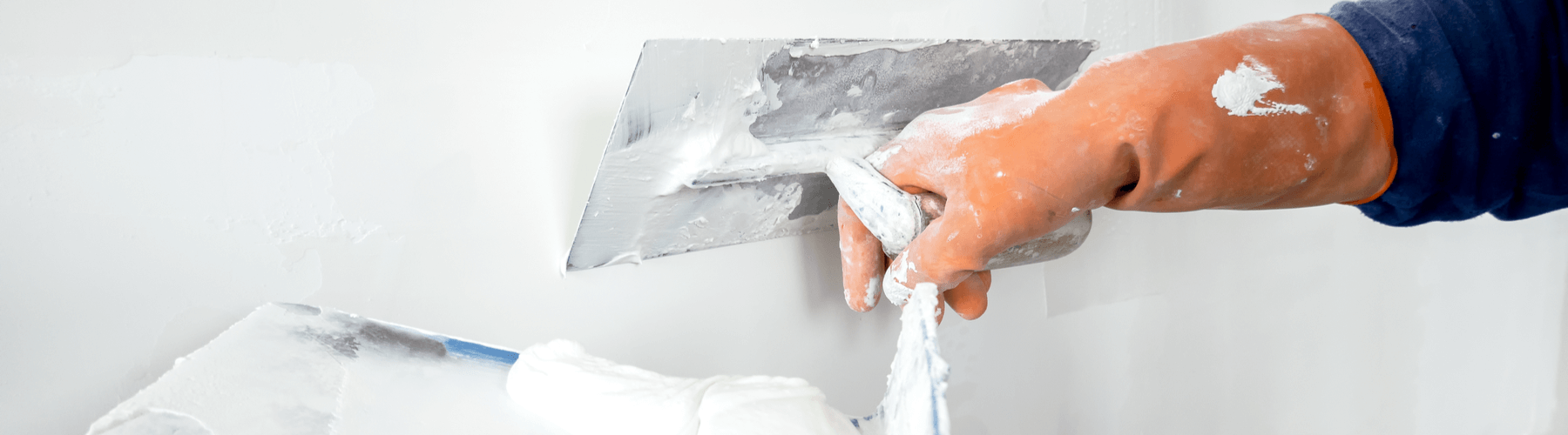 person applying plaster on wall
